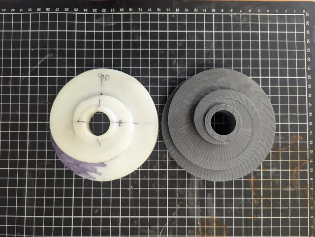 Original light-coloured counterbalance cable pulley beside the dark fabricated replacement